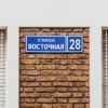 Стандартная адресная табличка из двух слоёв композита на кирпичной стене.