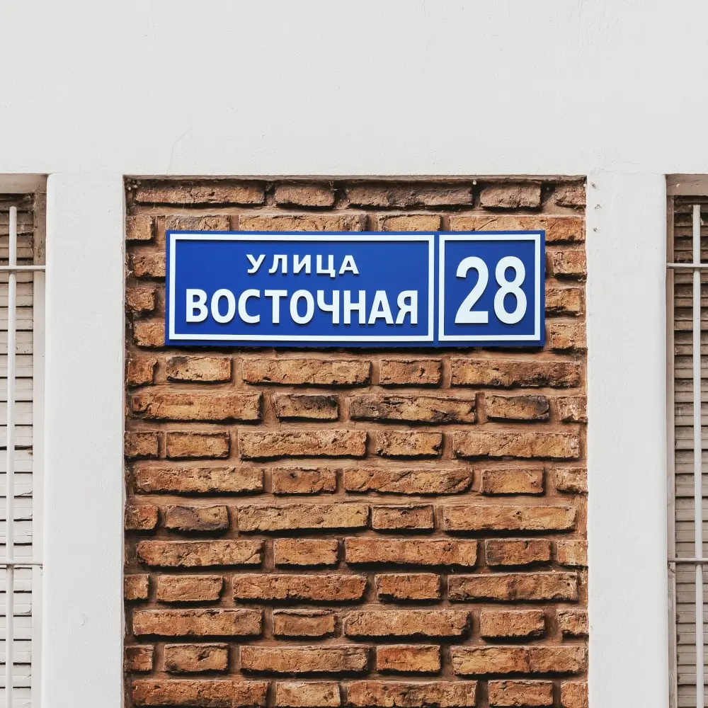 Стандартная адресная табличка из двух слоёв композита на кирпичной стене.