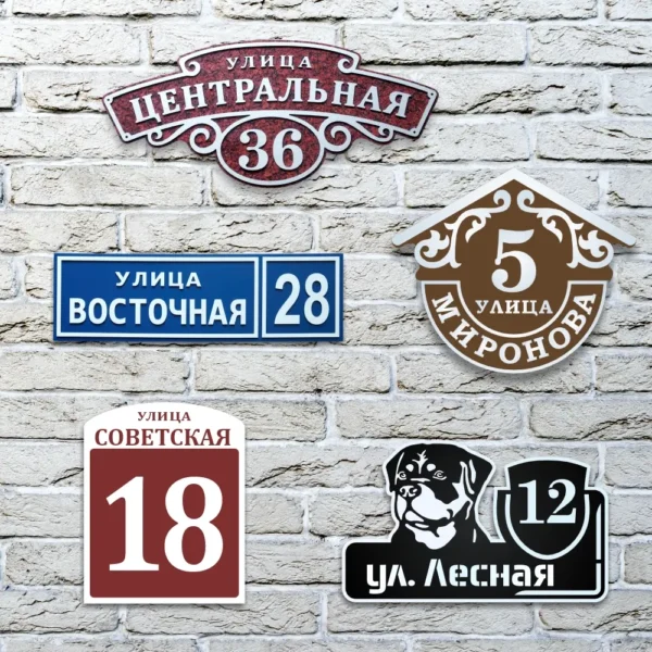Варианты адресных табличек на дом на белой кирпичной стене.